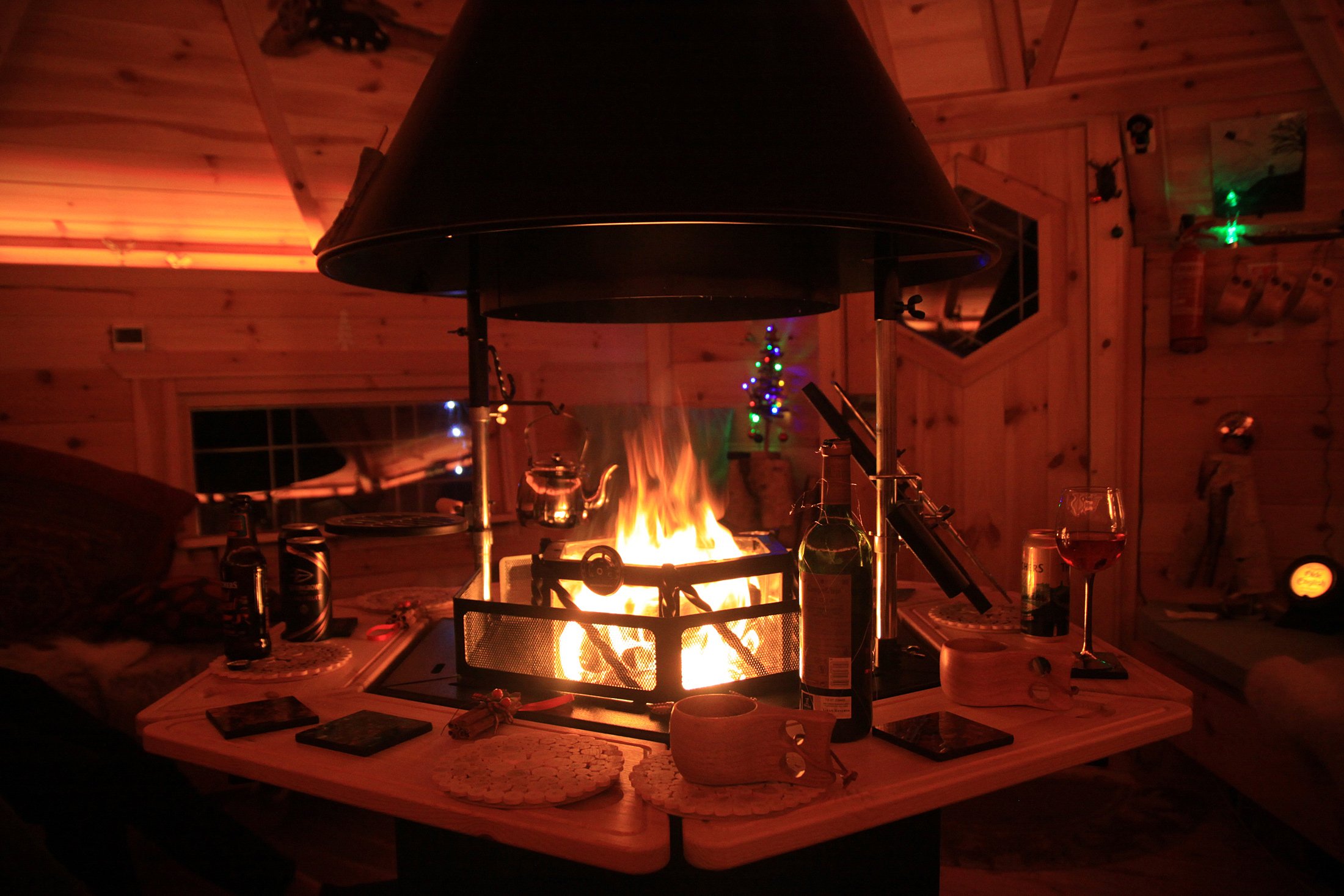 Interior of a BBQ cabin with fire lit, kuksa cups, wine & beers