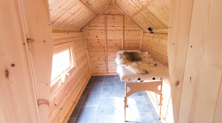 Interior of timber cabin treatment room by Arctic Cabins, with treatment bed and reindeer skins