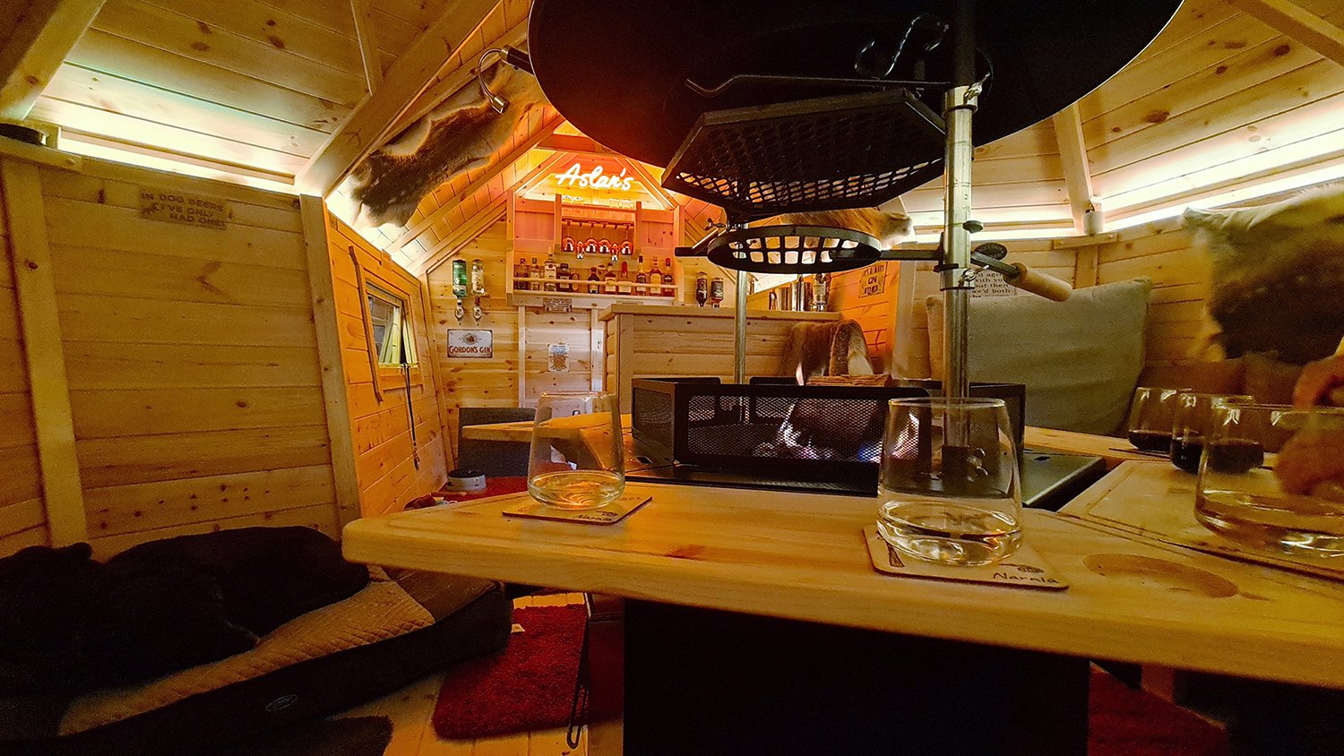 Inside Arctic Cabins Man Cave Garden Bar with BBQ unit and neon sign decoration