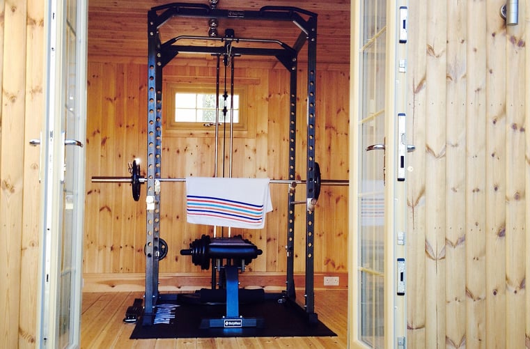 Interior of garden timber cabin with door open and gym equipment