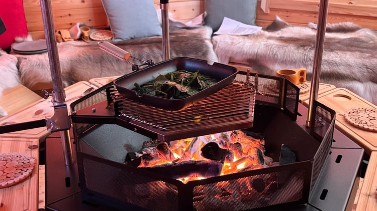 A pan of spinach cooking over a hexagonal BBQ grill