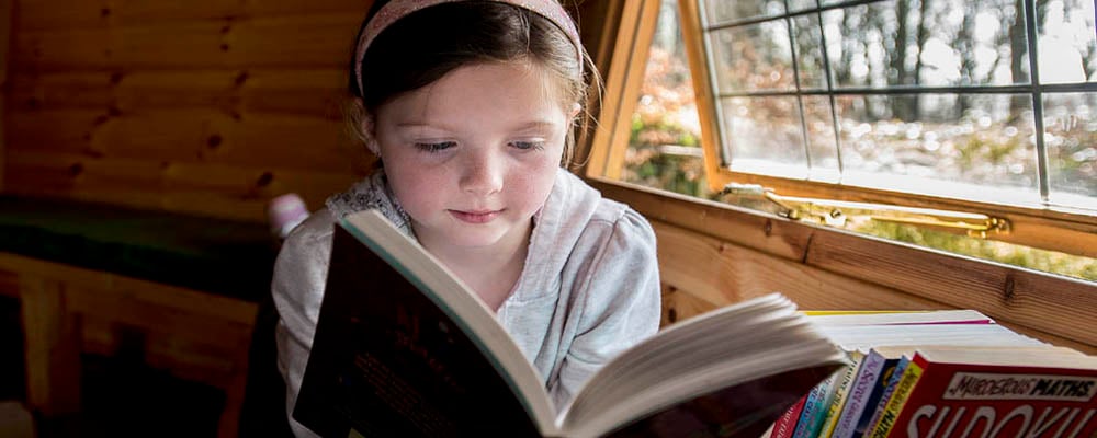 Interior of timber cabin with girl reading