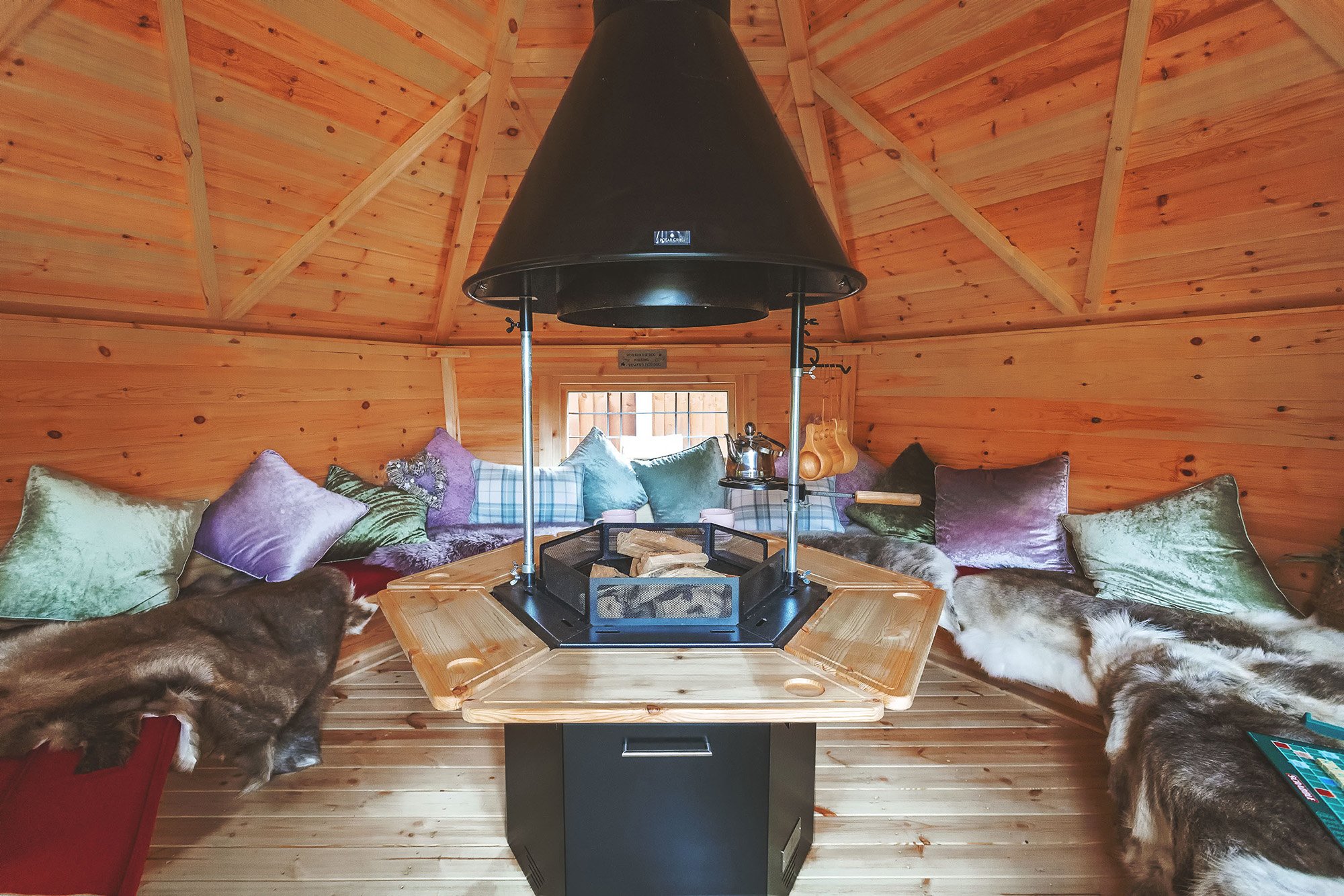 Interior of a cosy 10m² Arctic Cabin BBQ house with reindeer skins and cushions as decoration