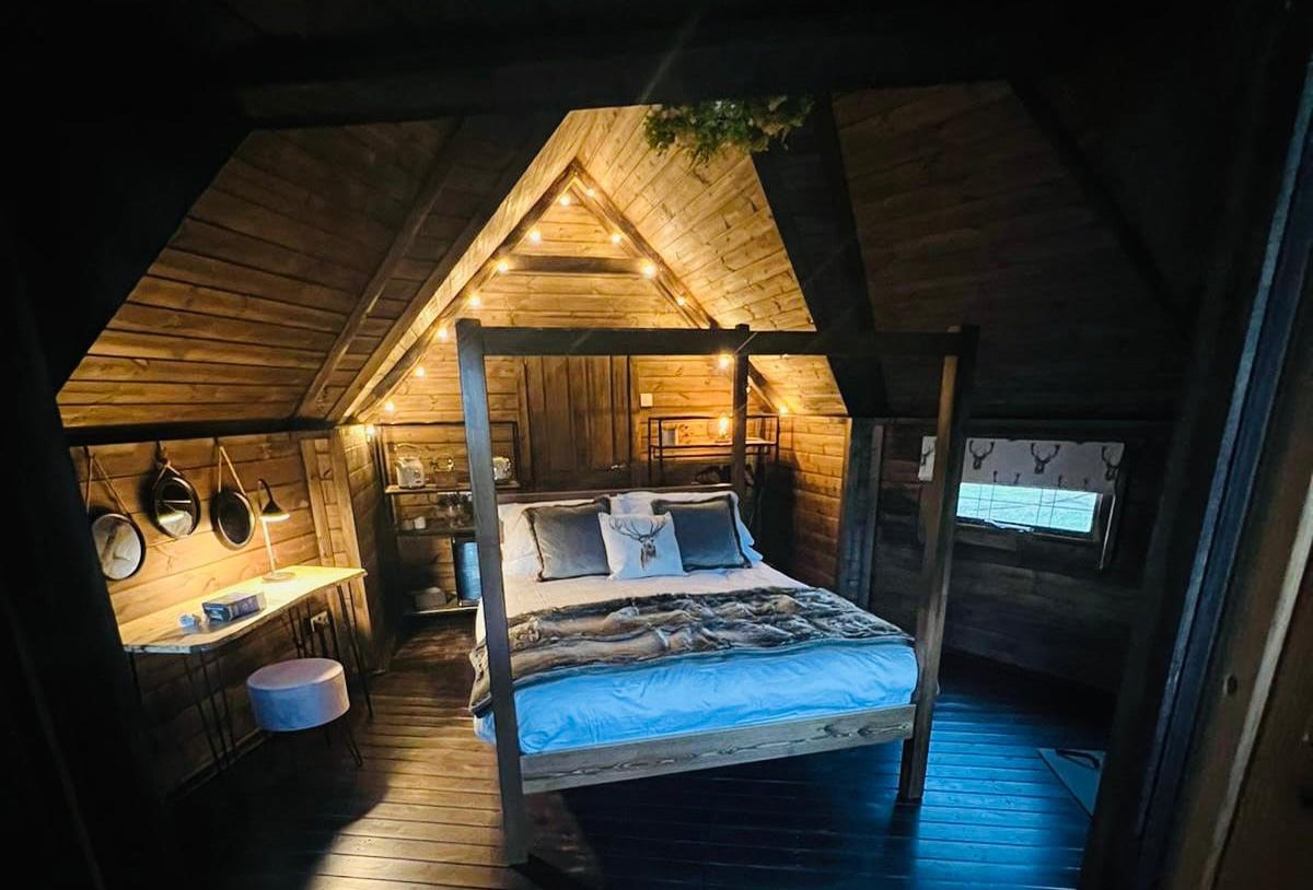 Interior of a dimly-lit Timber Garden Room Cabin with four poster bed