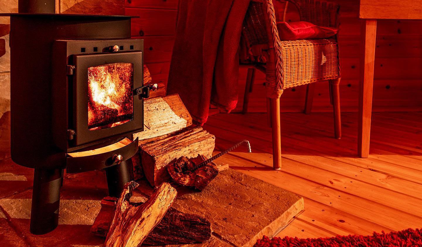 Log Burner inside Log Garden Cabin with chair and logs nearby