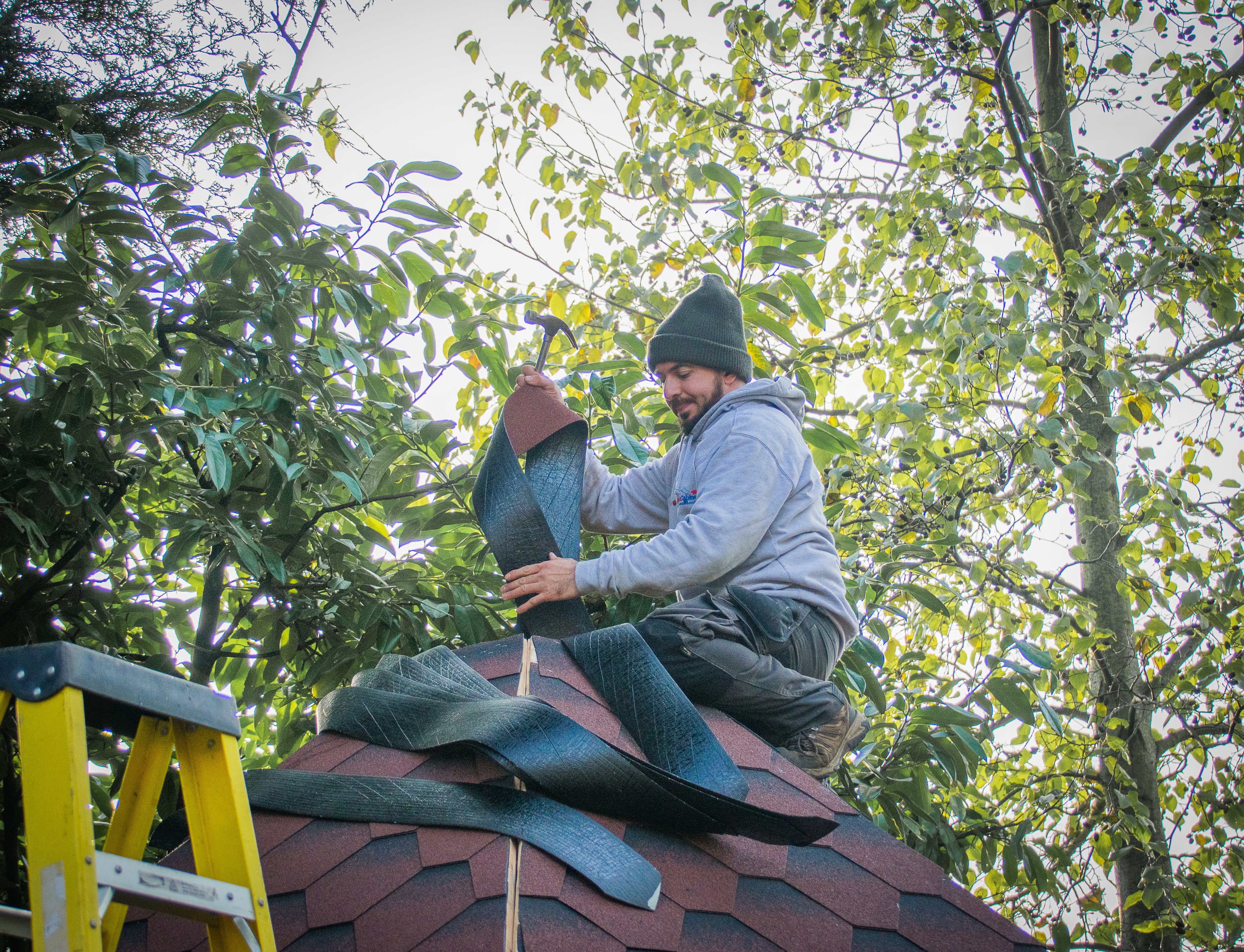 Arctic Cabins installer applying roof felt to BBQ hut, Nottingham show site