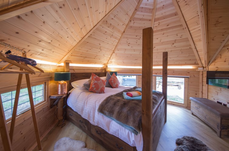 Log Cabin Garden Room Bedroom interior with wooden 4 poster bed and soft furnishings