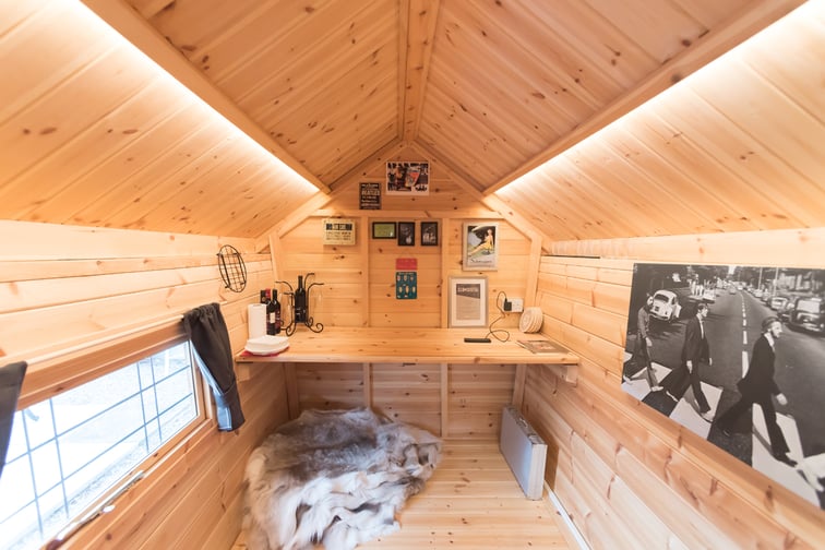 Interior of Timber Scandinavian Garden Office with desk, pictures and rugs