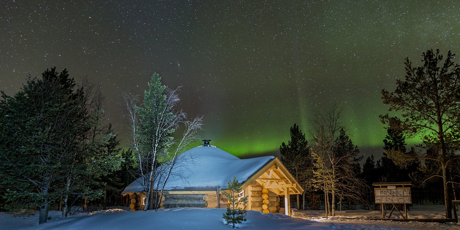 Snow-covered Grillkota BBQ hut in Arctic Finland with Northern Lights seen in the background