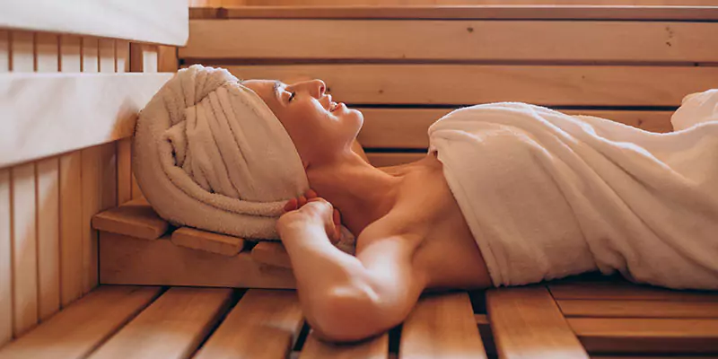 woman reclining inside a sauna room by arctic cabins